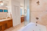 Enjoy twin vanities with granite counter tops, tile flooring, tropical wallpaper, a shower and large over-sized soaking tub